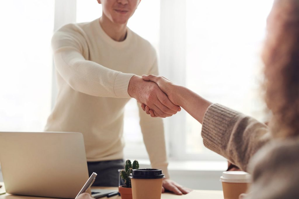 man-and-woman-near-table-3184465 Close-up of professionals shaking hands over coffee in a modern office.